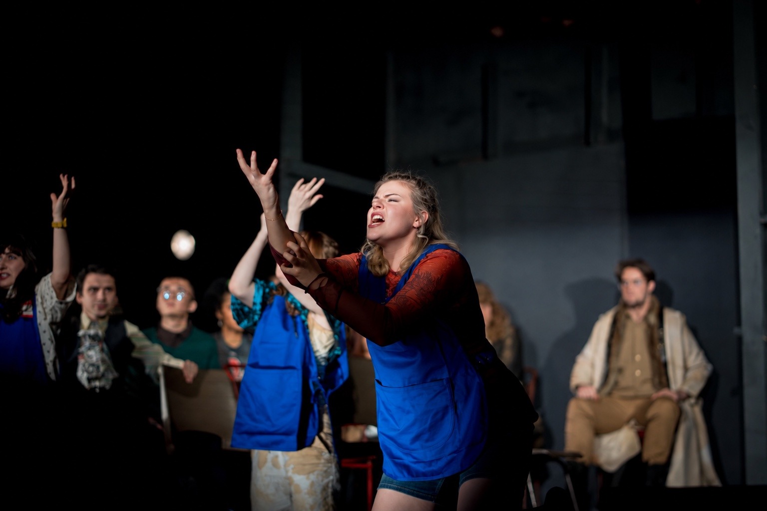 Lottie Craven as Abigail Williams in The Crucible, reaching upwards on stage